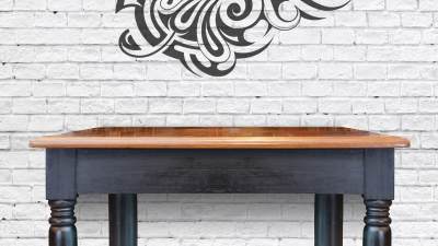 A wood desk placed against a white brick wall with a Maori pattern on it.