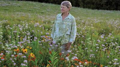 Carol Vanden Bosch Rottman ’60 walking through a field of flowers.