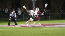 Calvin University men's lacrosse player with his stick in the air