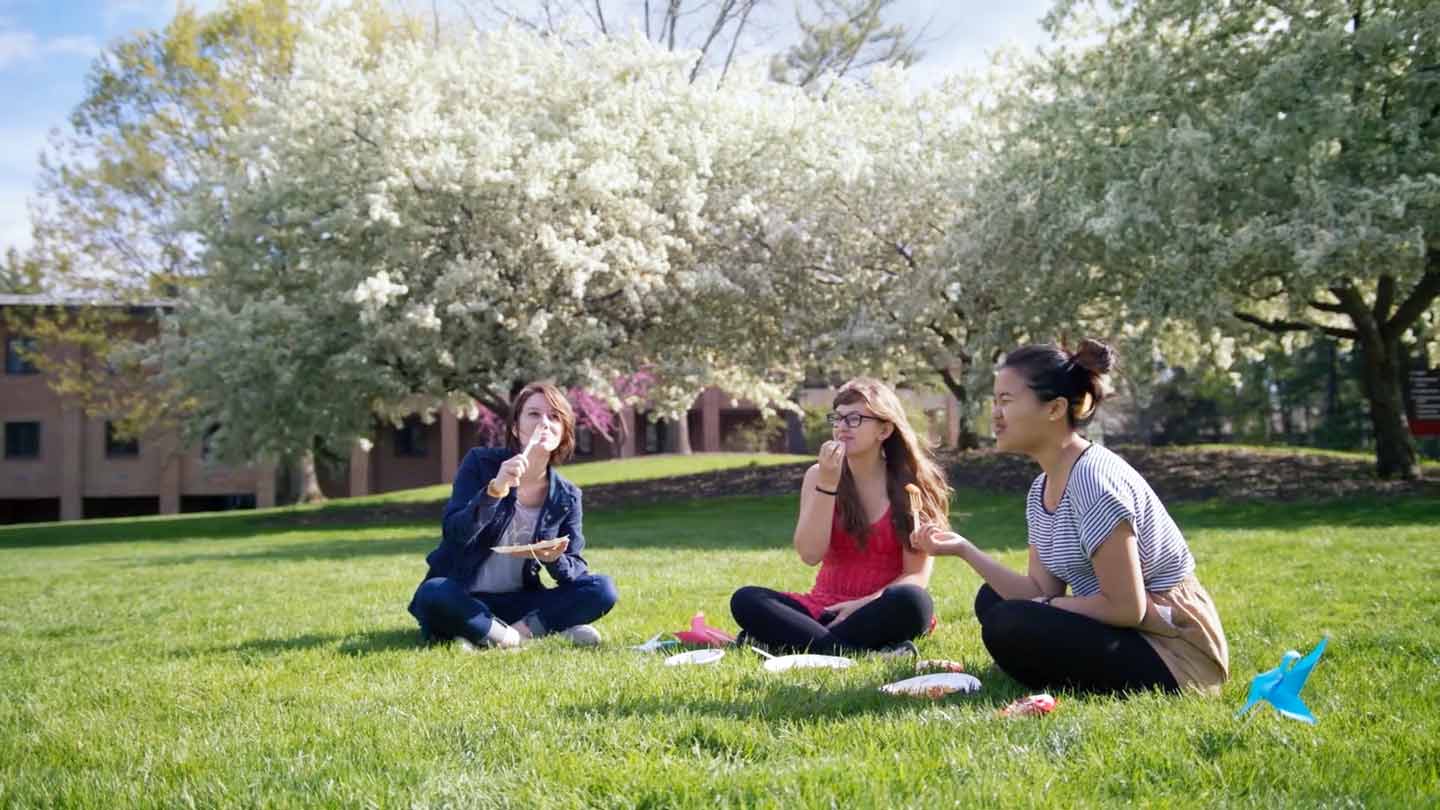 Three diverse, female students enjoying the day on the Commons Lawn.