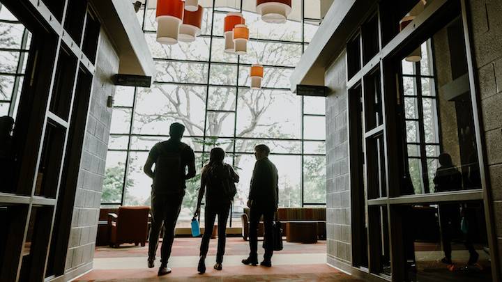 A trio of students walking through a hall