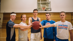 Group of male athletes hold a basketball
