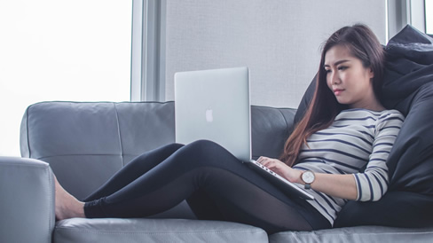 Young woman sitting in couch at laptop
