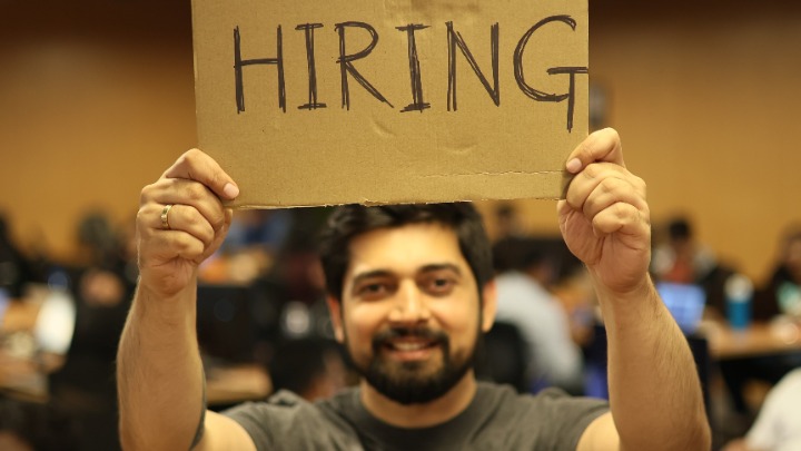 Man holding hiring sign.