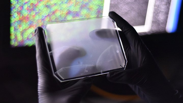 A plastic holder with a surgical glove holding it and a bright computer image in the background