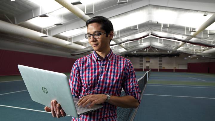 Male student with laptop in the Huizenga Tennis and Track Center