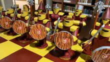 A row of chess pieces on a maroon and gold board with the Calvin logo on them.