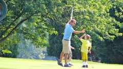 Tyler high-fives a student he's teaching to play golf