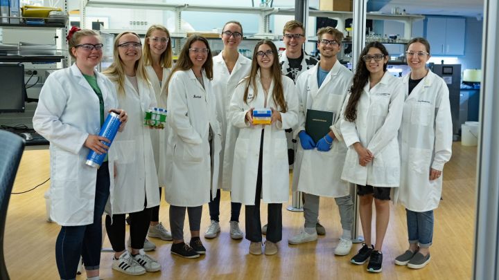 Students and professor posing as a group in a science lab.
