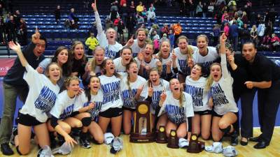 The Calvin women's volleyball team posing joyously with a trophy.