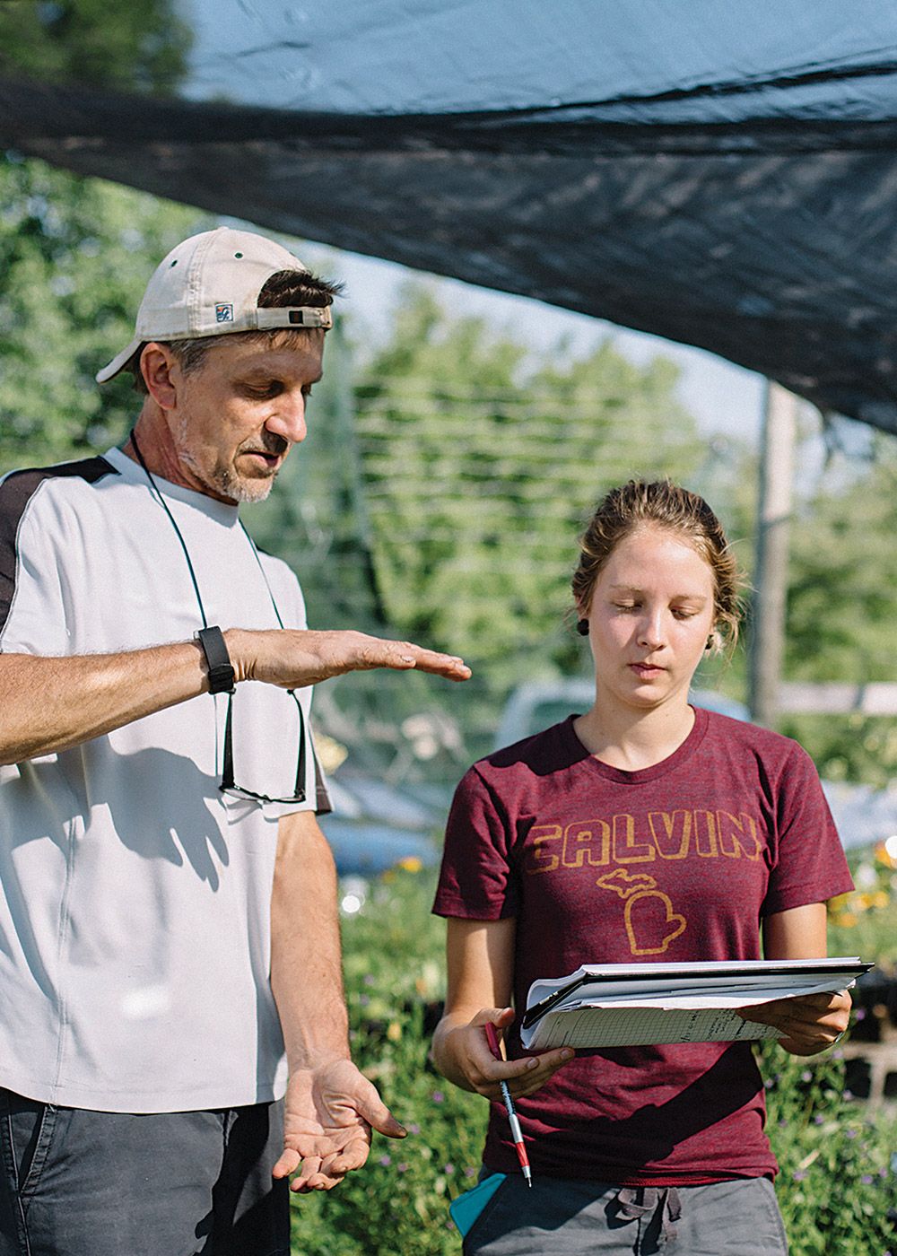 Calvin professor David Warners instructs a student out in the field, gesturing with his hands.