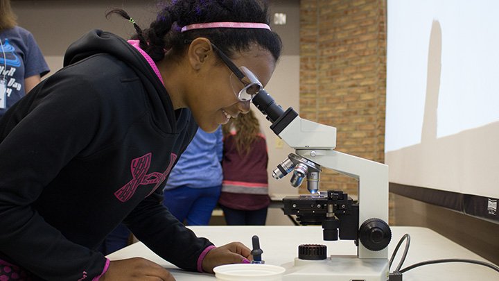 A student looks through a microscope.