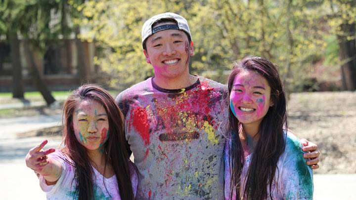 International students posing for the camera, covered in mutli-colored paint