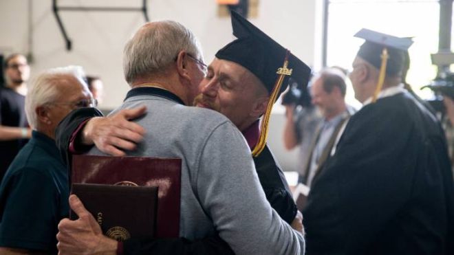 A graduate hugs a family member after receiving his degree.