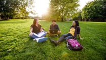 Three Calvin University students sitting on Commons Lawn studying in Grand Rapids, Michigan