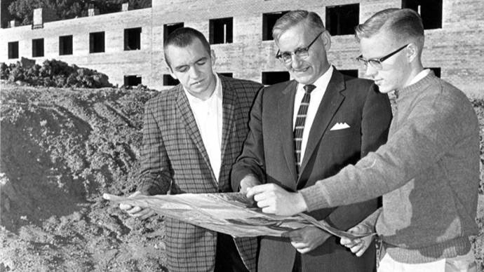 Three men review blueprints at the Knollcrest Campus construction site.