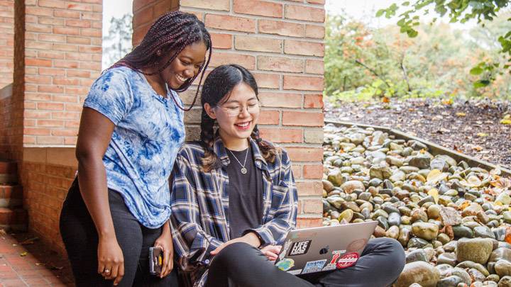 Two Calvin University students studying outside with laptop