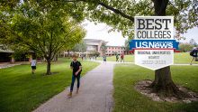A student walks on a path on Calvin University's park-like campus, a U.S. News badge is overlayed.