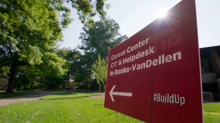 A maroon yard sign points the way to the Career Center, CIT, and Helpdesk located temporarily in the Rooks-VanDellen dorm.