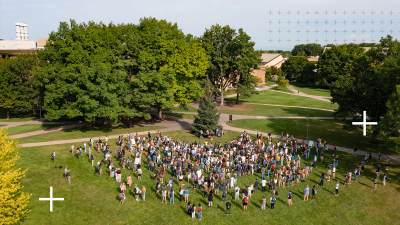 A wide shot of Calvin's campus showing many students gathered on the lawn