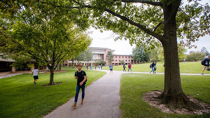 Students walking on paths crossing through the center of Calvin University's main campus on a fall d