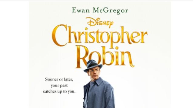 Ewan McGregor stands underneath the logo of Christopher robin in a hat, looking off at an indistinct