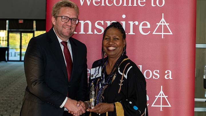President Wiebe Boer shakes hands with Rev. Dr. Michelle Loyd-Paige who is holding a trophy.