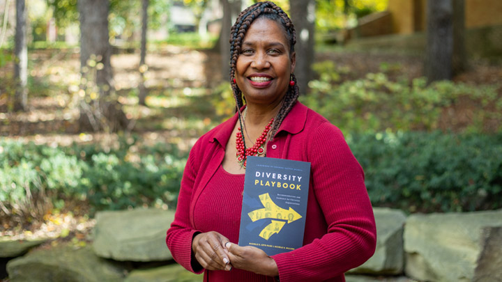 Photo of Michelle Loyd-Paige holding her new book outdoors on Calvin's campus.