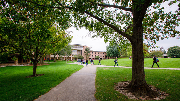 A wide shot of students walking on the path near the Commons Lawn at Calvin University.