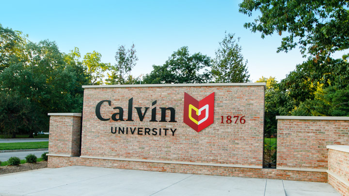 The entrance sign to Calvin University with green trees in the background.