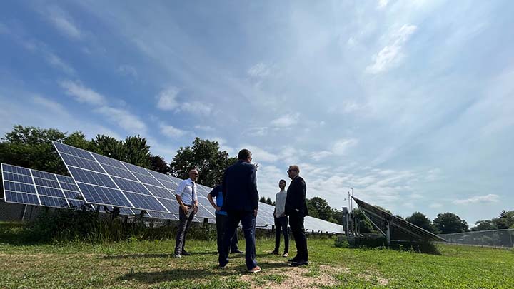 A group of men in business attire standing outside near solar panels.
