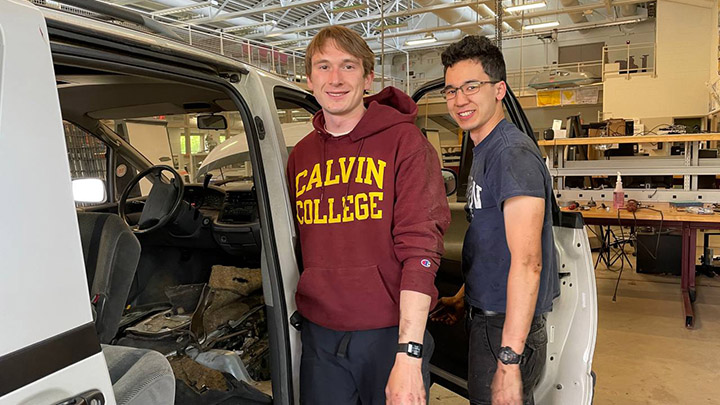 Two Calvin students standing in front of a minivan