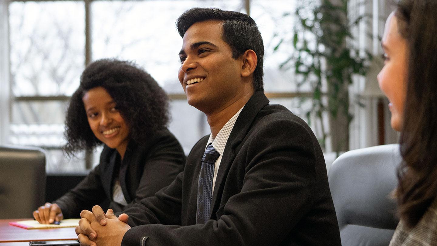 Students in professional clothing smiling, looking off into the distance
