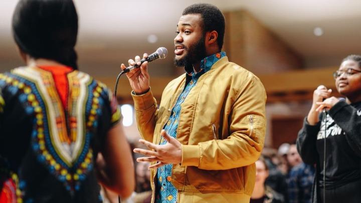 Male Calvin University student of color speaking at a microphone in the Calvin chapel