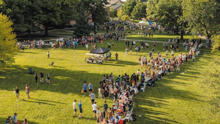 Hundreds of students gather around a green space in the middle of Calvin University's campus.
