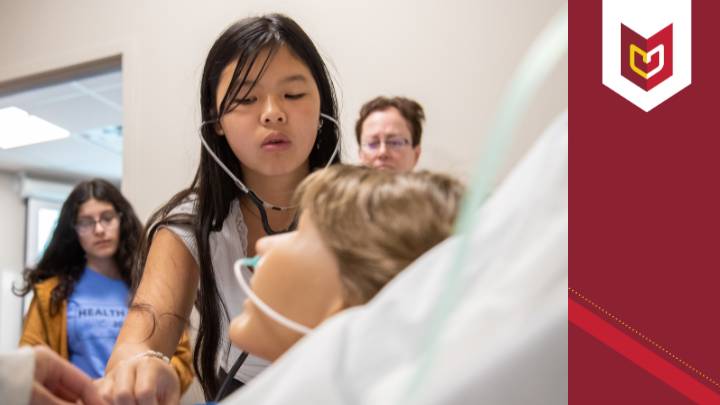 A girl checks the vitals on a manikin during Health Camp 2023 at Calvin University.