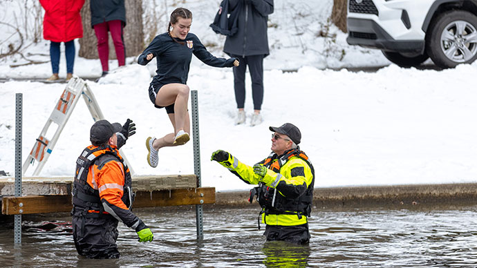 A young lady jumps from a short dock and into the freezing Sem Pond.