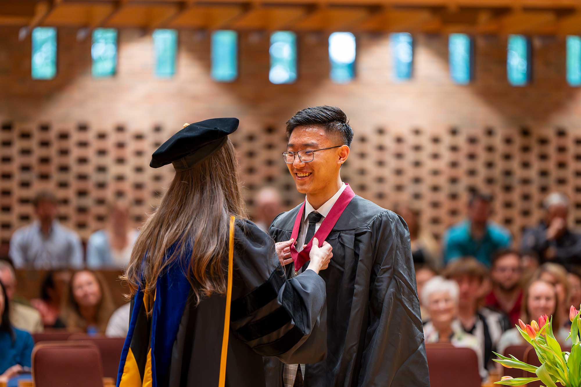 A professor places a medal around an honors graduate's neck at honors convocation.