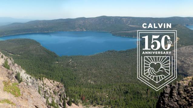 View from above of a lake surrounded by evergreen forests and cliffs, with the Calvin 150th anniversary logo overlay.