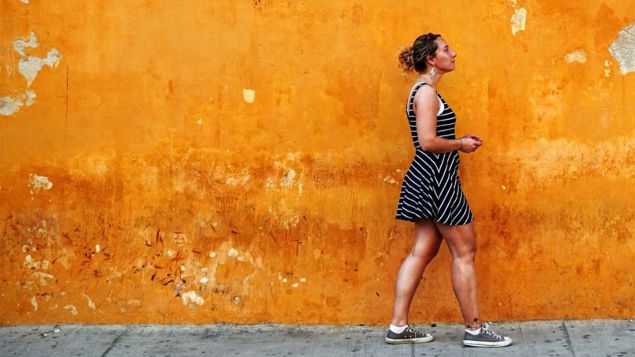 Woman walking past an orange wall
