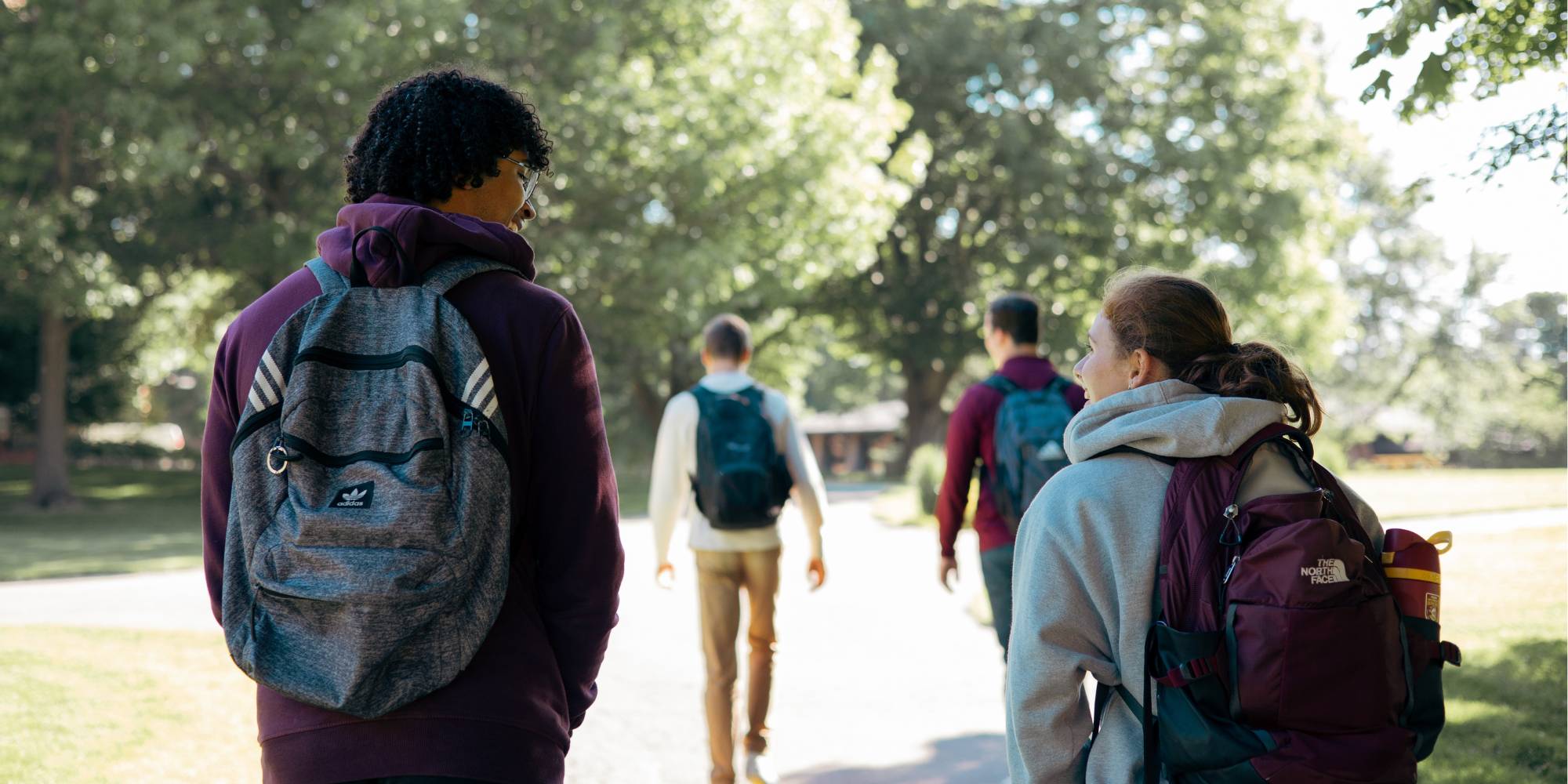 Students walk with backpacks on the Calvin University campus paths.