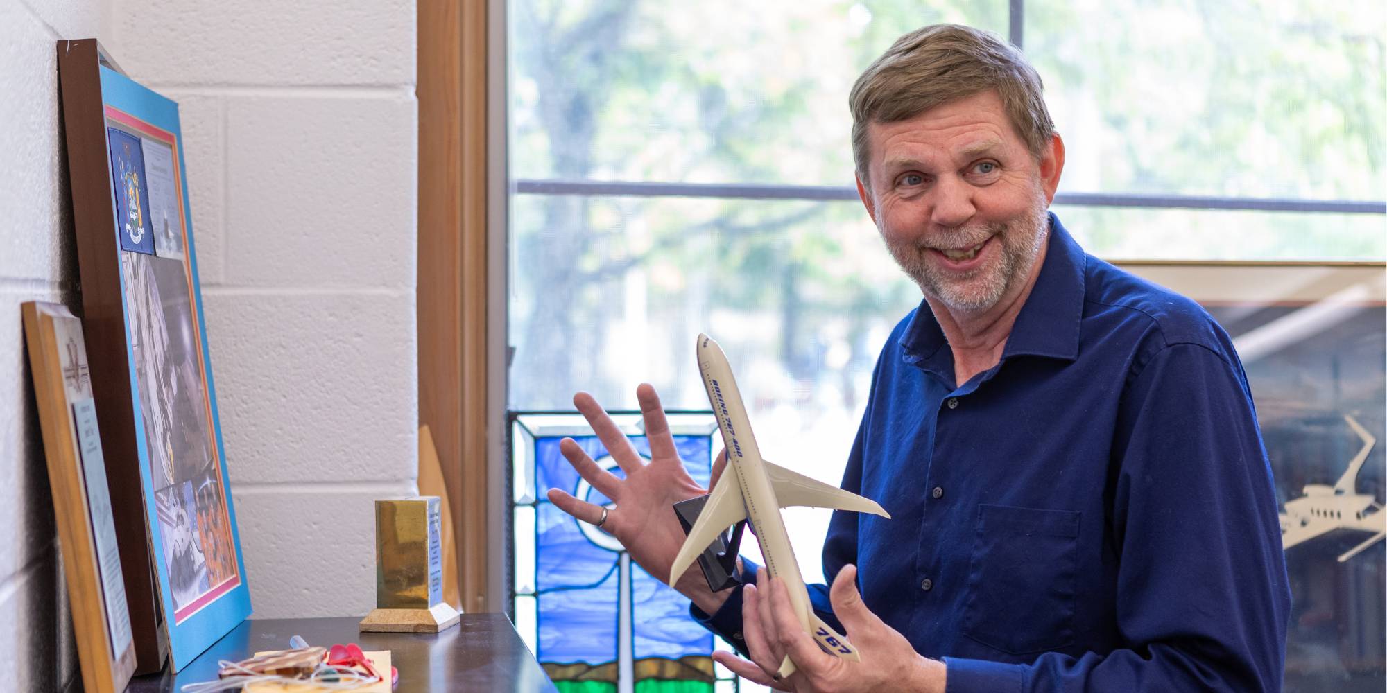 Professor Ken Visser smiles with a model airplane in his hand.