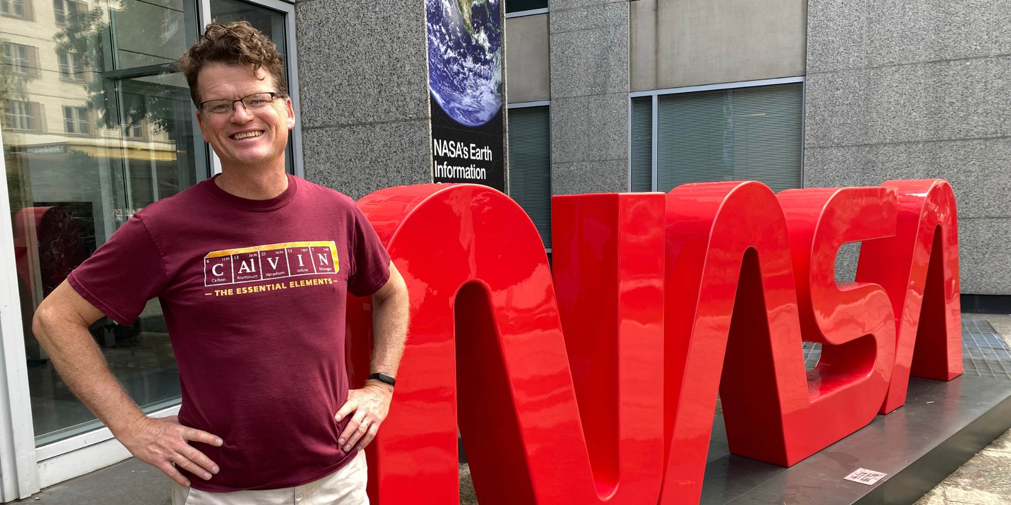 Herb Fynewever, chemistry professor at Calvin University, standing next to a NASA sign.