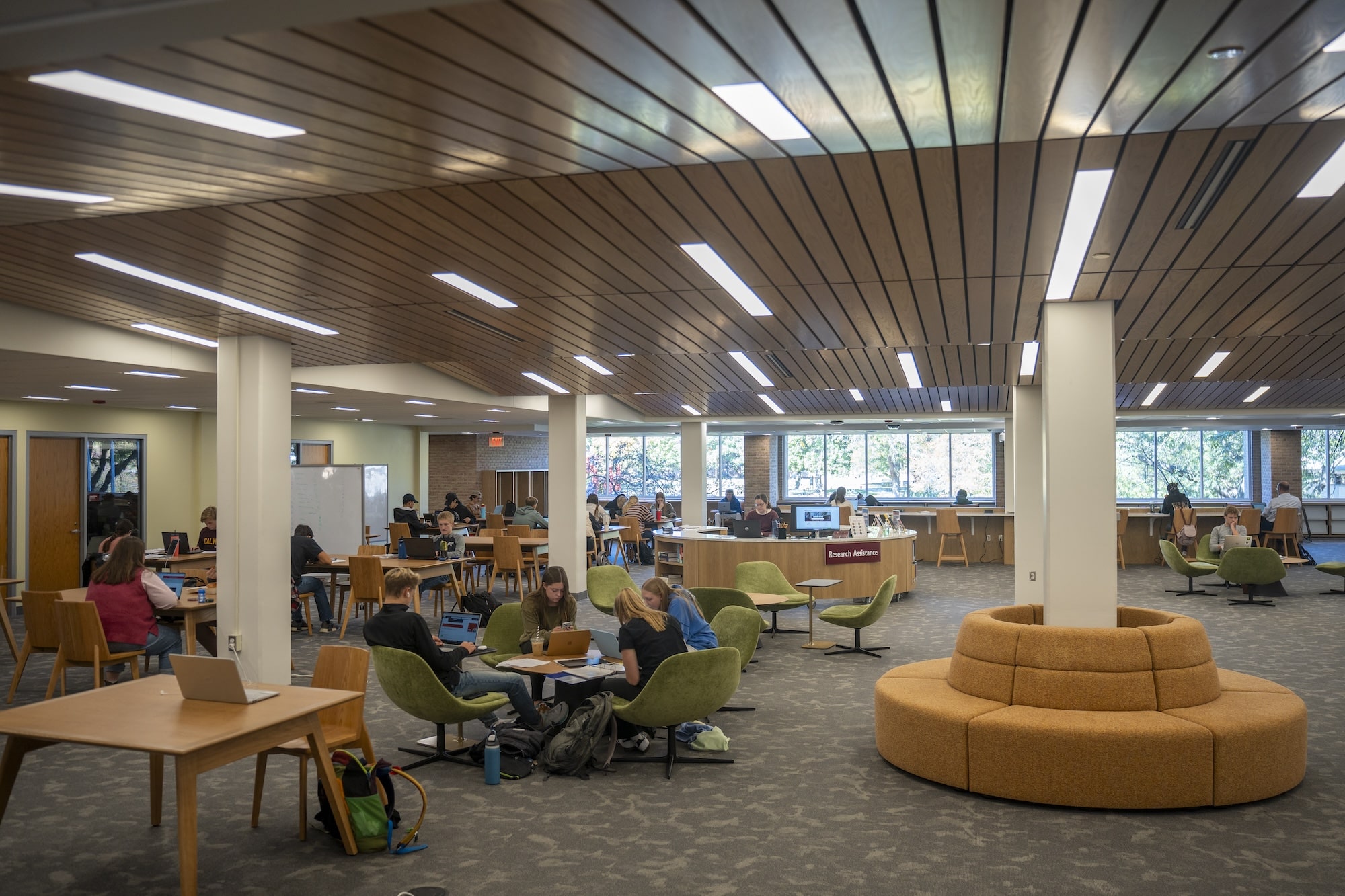 Calvin University students studying in newly-renovated library space, sitting on chairs and reading books