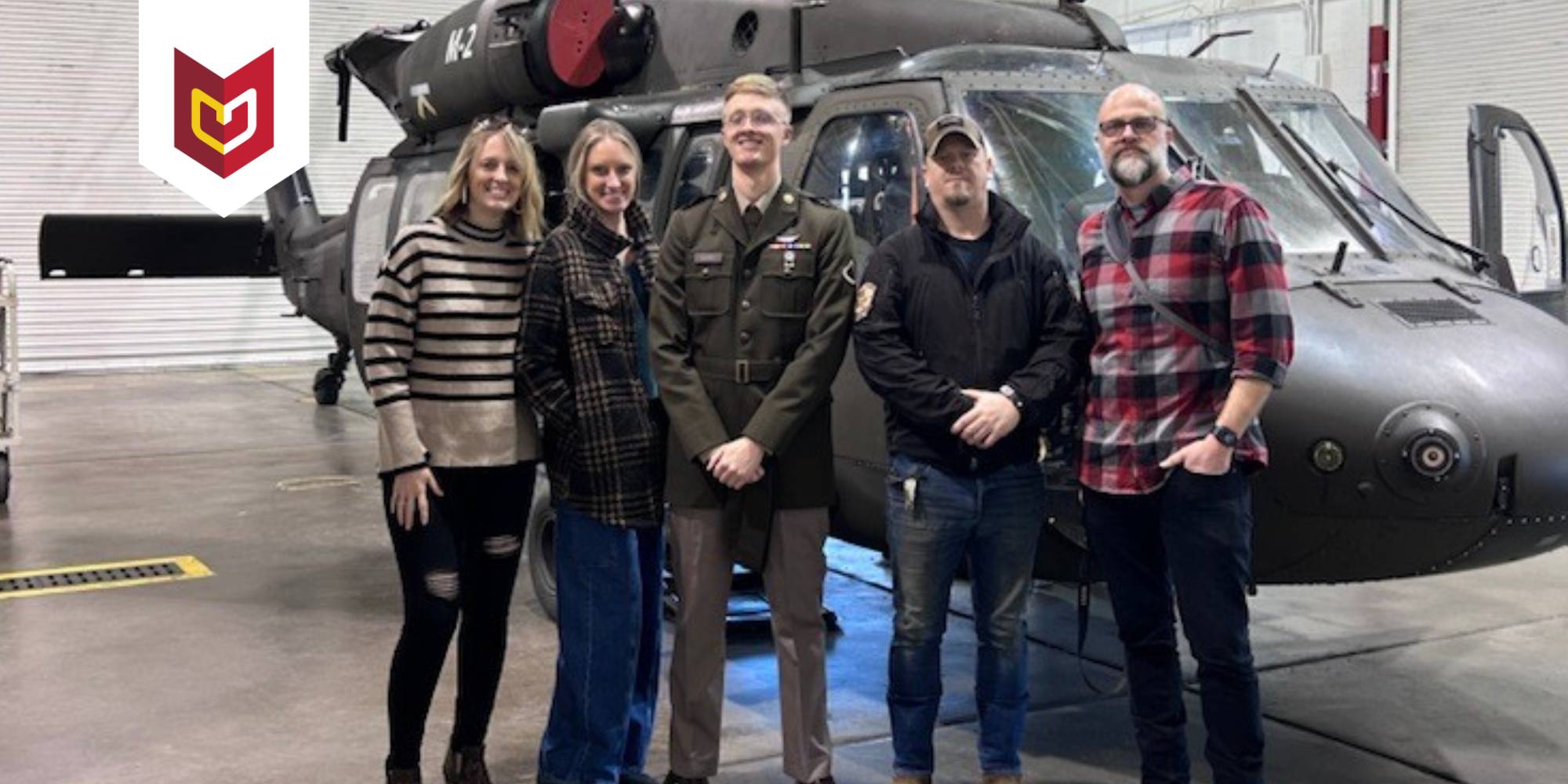 Reuben Arends, a student at Calvin University and member of Army National Guard, stands with family in front of a helicopter.