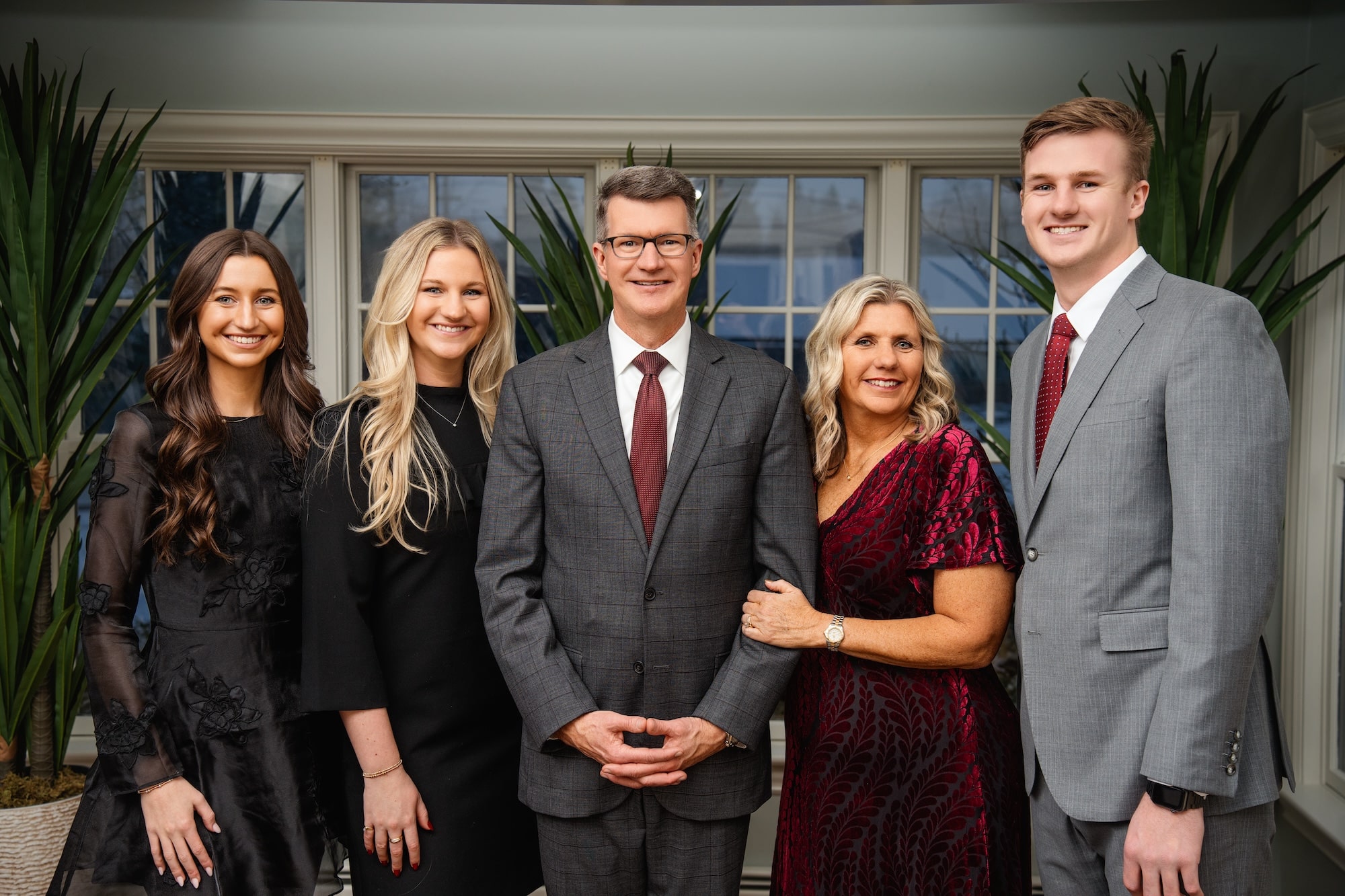 Family of President Elzinga, dressed for Christmas standing in front of their home window
