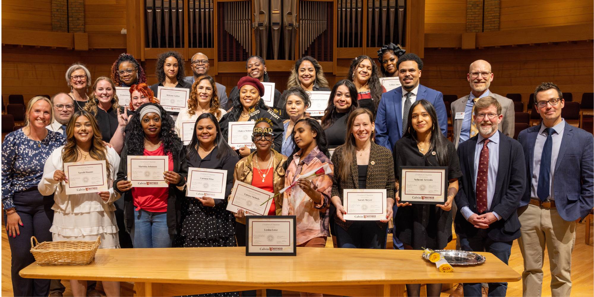 The Wayfinder Class of 2025 standing with professors and administrators of the program during their graduation ceremony.