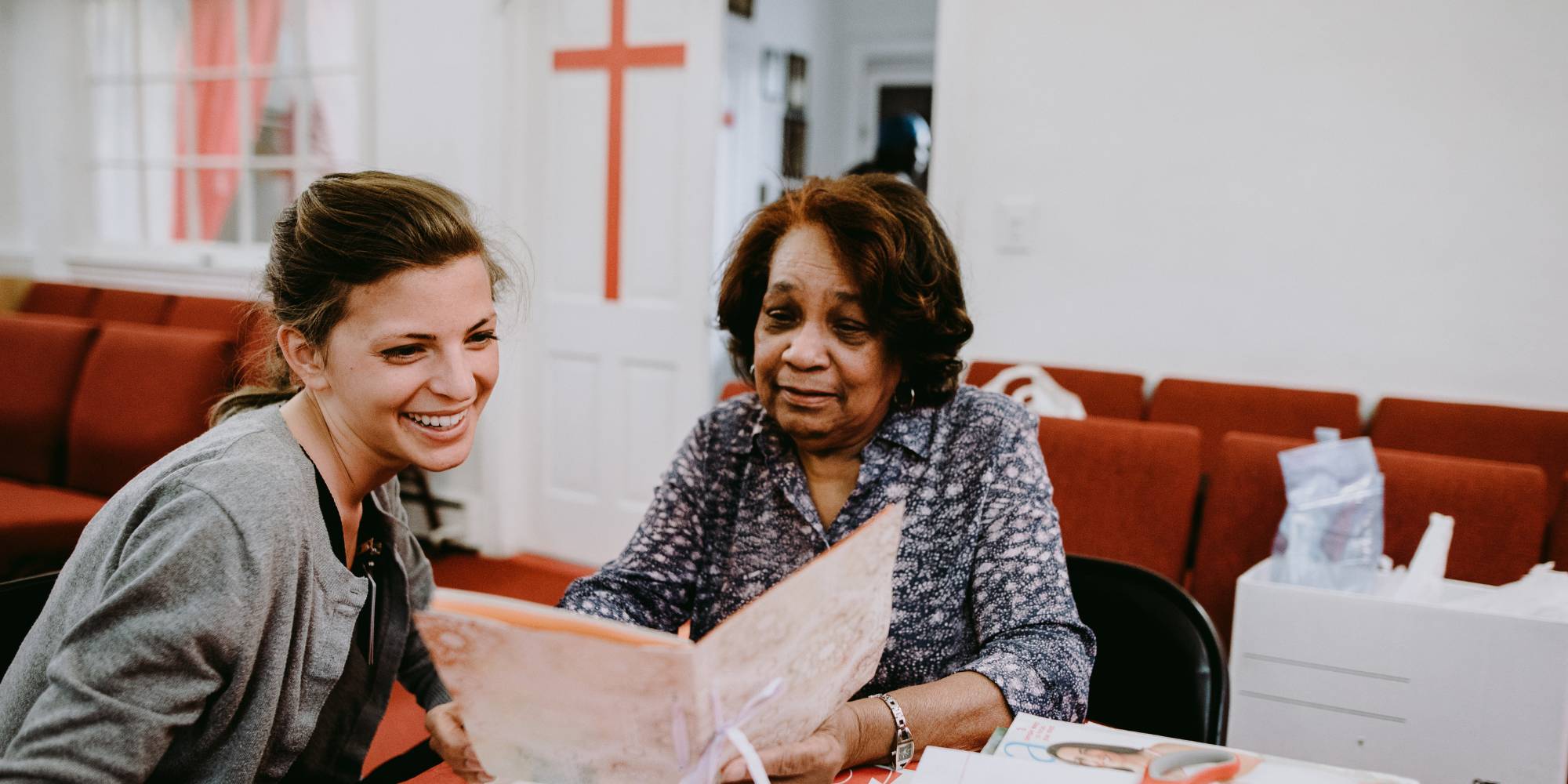 Two women talking together while looking at a book