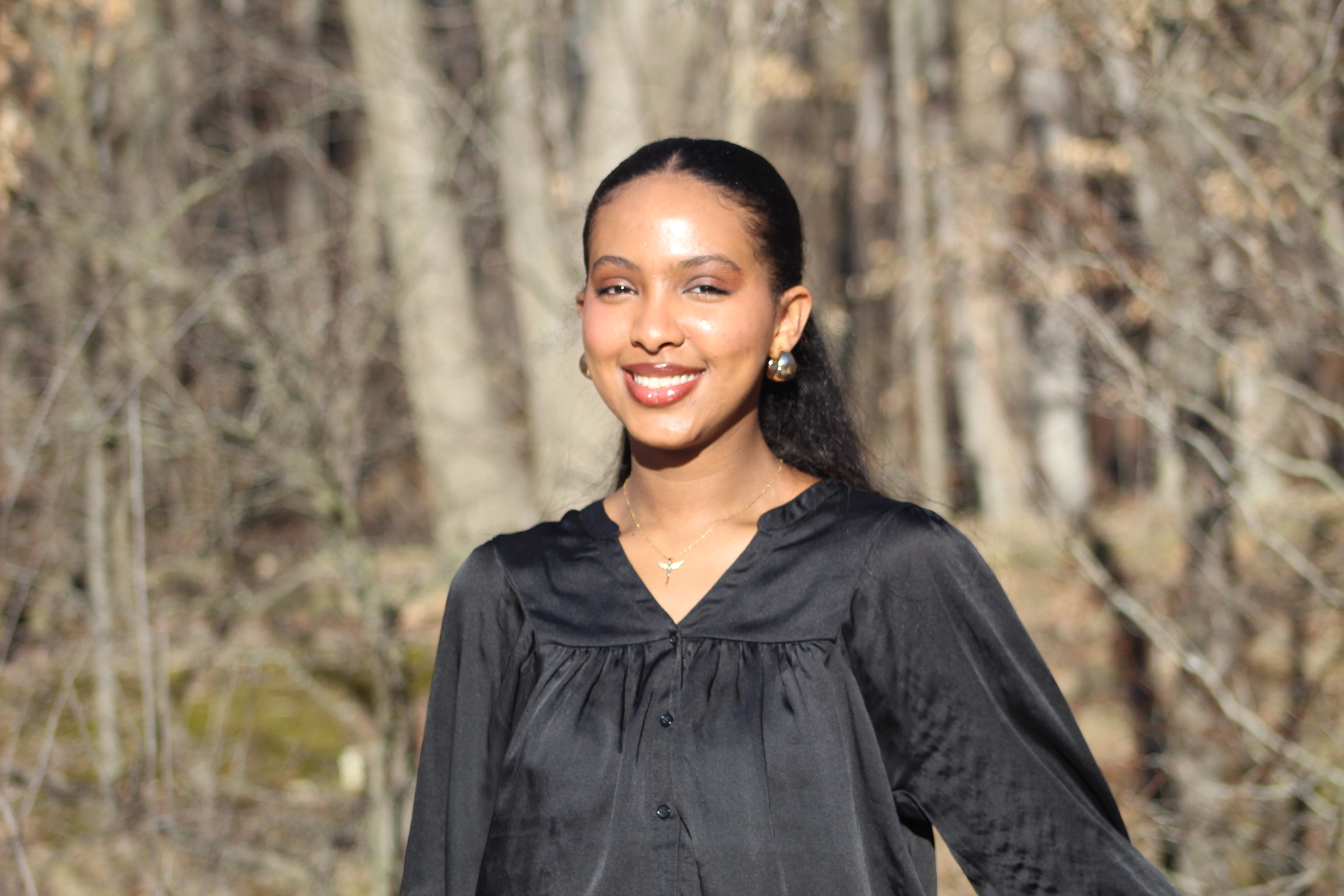 Girl tanding near sunlit woods