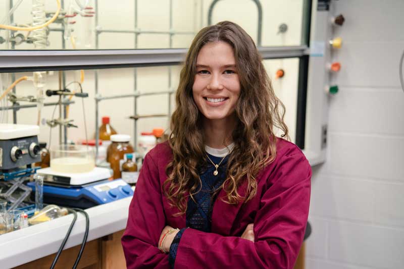Aerin Baker, Calvin student and Goldwater Scholar, poses with arms crossed in a science lab.